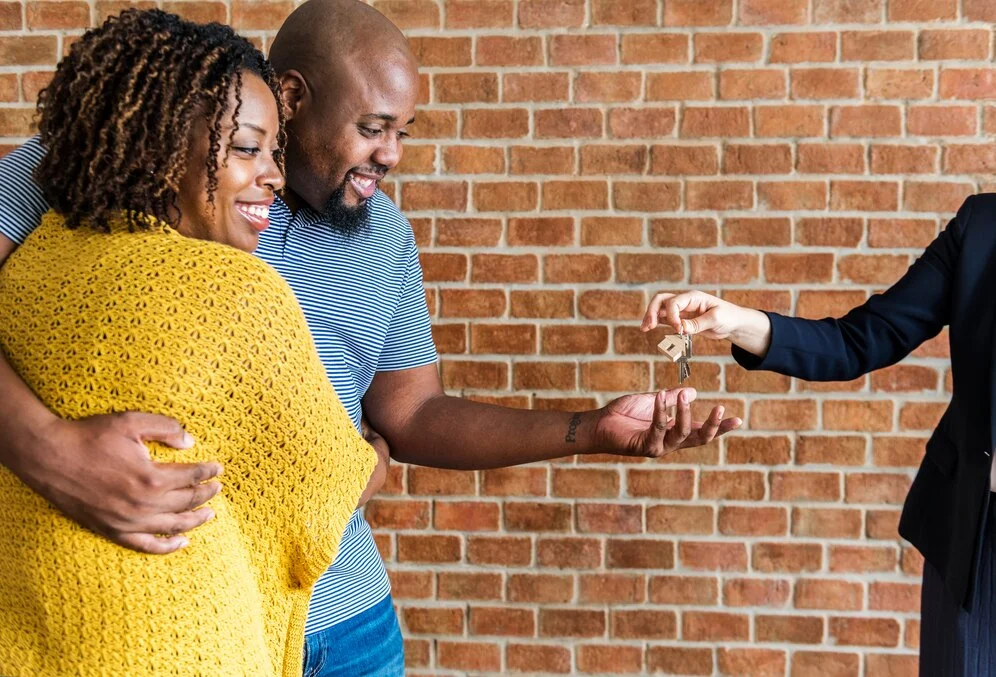 Un couple souriant reçoit les clés de leur nouveau logement, symbolisant un moment de bonheur et d'accomplissement dans la location de leur maison.