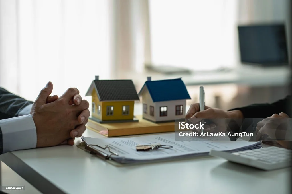 Une discussion professionnelle dans le domaine de l'immobilier illustrant la gestion immobilière. Deux personnes sont en train de discuter, accompagnées de maquettes de maisons.