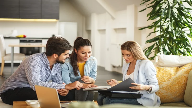 Un couple en pleine discussion avec une conseillère, illustrant une étape clé dans la gestion ou l'acquisition d'un bien immobilier.