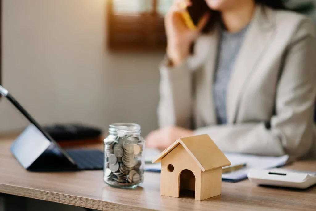 déblocage pel : femme au téléphone devant un bocal rempli de pièces de monnaie et une petite maison