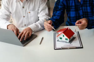 fiscalité crowdfunding : deux personnes devant un ordinateur portable et une petite maison