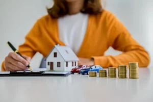 déclaration pinel : femme tenant un stylo devant une petite maison, des petites voitures et des pièces de monnaie