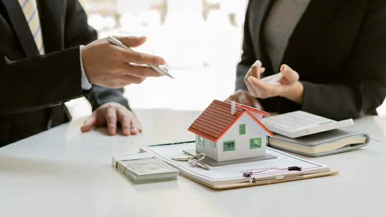 créer SCI seul : personne tenant un stylo et pointant une petite maison devant une autre personne qui tend la main