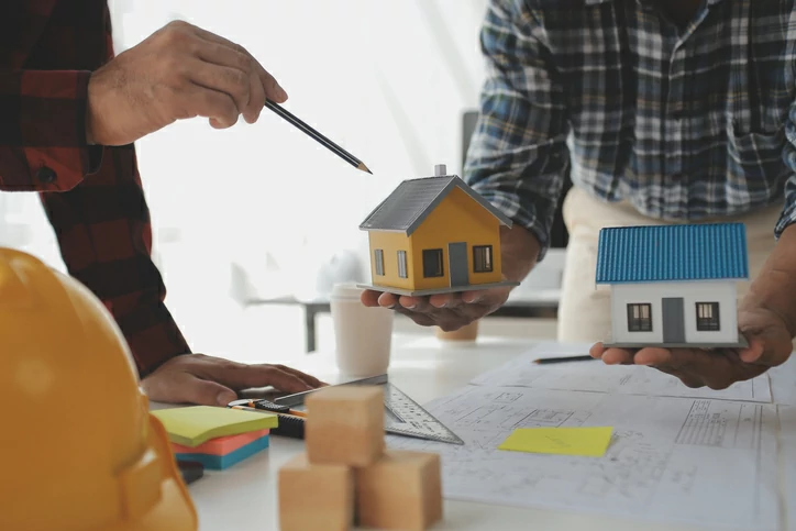 devenir rentier scpi : personne tenant une petite maison et une main tenant un crayon