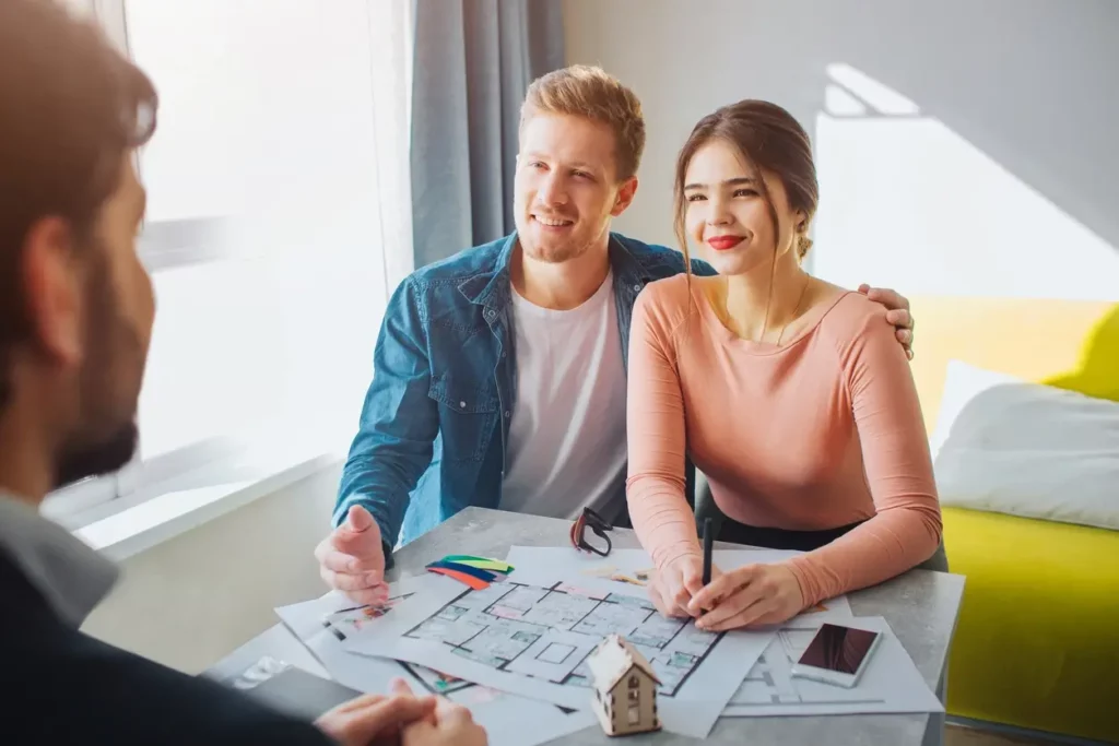 Image d'un couple chez une agence immobilière demandant où acheter le moins cher en France pour acquérir une résidence principale