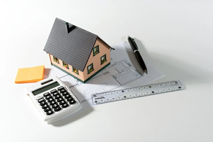 renovation thermique : petite maison, calculatrice, règle, stylo et documents en papier avec des plans
